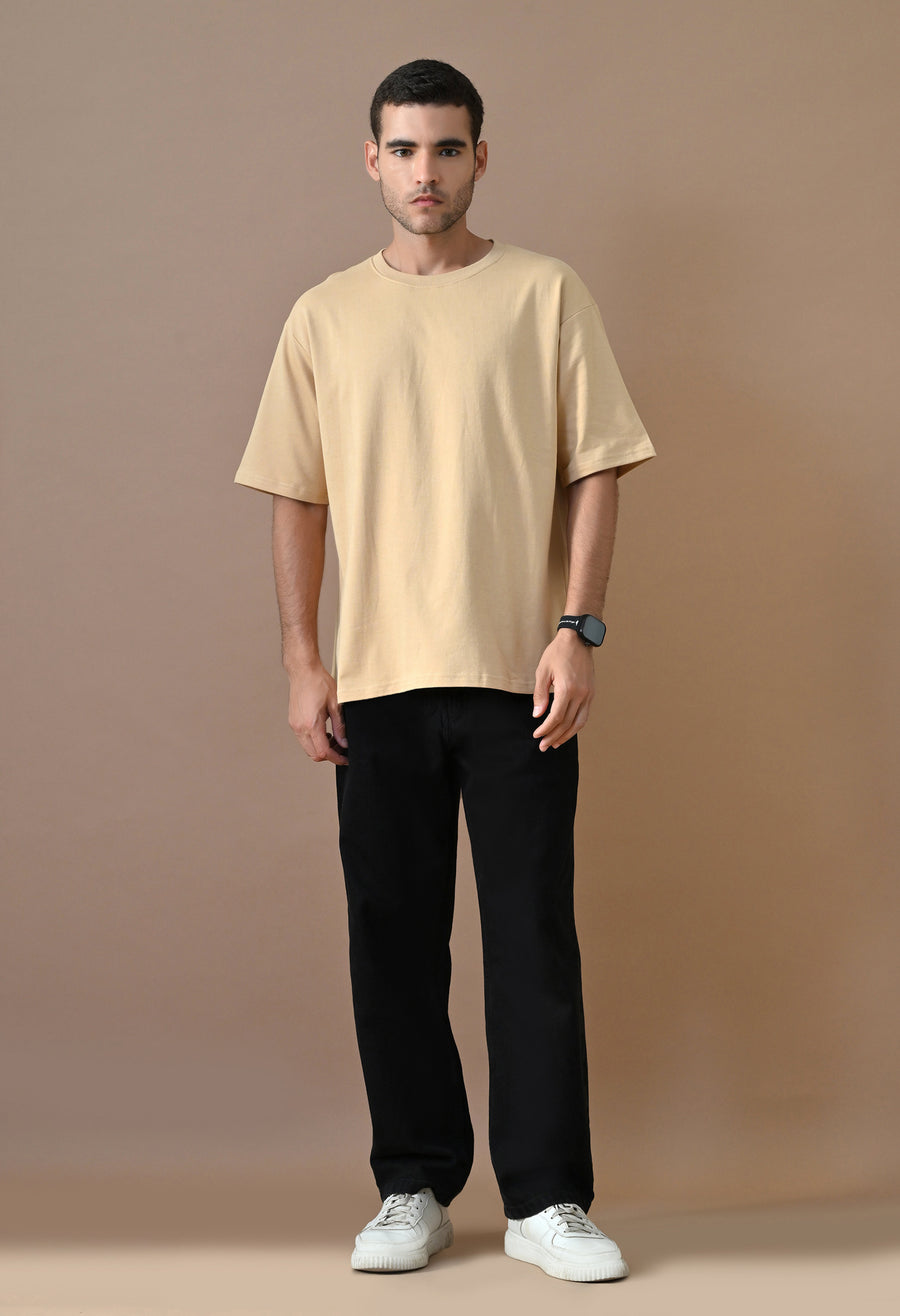 Man wearing OUTSYN Sand Beige Heavyweight Oversized T-Shirt with black trousers